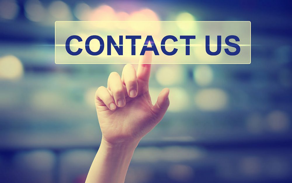Hand pressing a contact us button on blurred city lights background